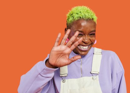 a black woman with green hair smiling shyly
